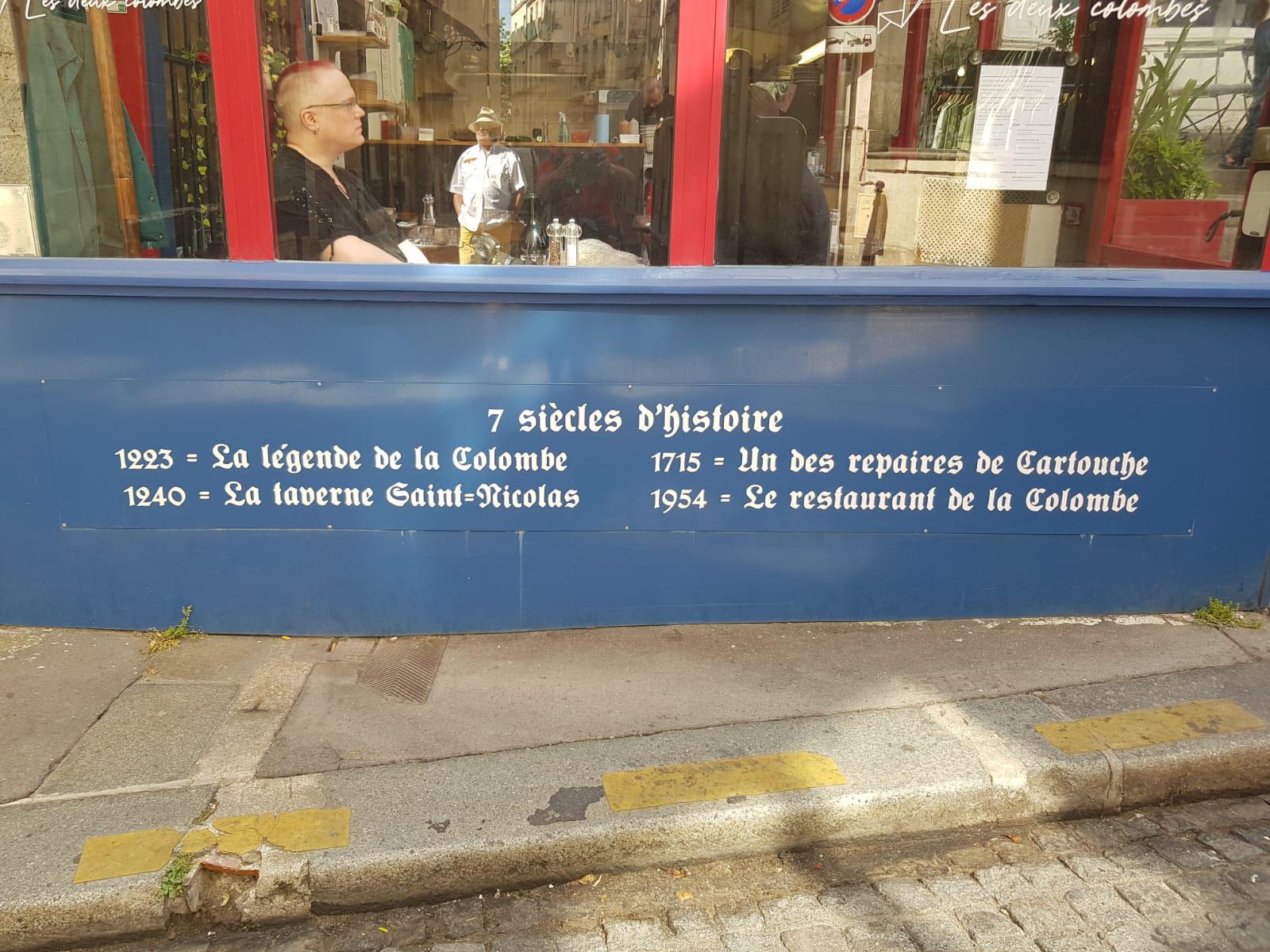 714541440_1290075556613601_5441328814818823536_n Blue storefront panel with white lettering reading '7 siècles d'histoire' and dates: 1923 La légende de la Colombe; 1940 La taverne Saint-Nicolas; 1715 Un des réparies de Cartouche; 1954 Le restaurant de la Colombe.