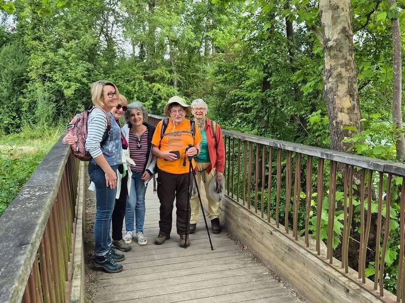 726145757_1302825005338656_8474499477181733152_n Group of five hikers posing on a wooden forest boardwalk with backpacks and trekking poles, smiling at the camera.