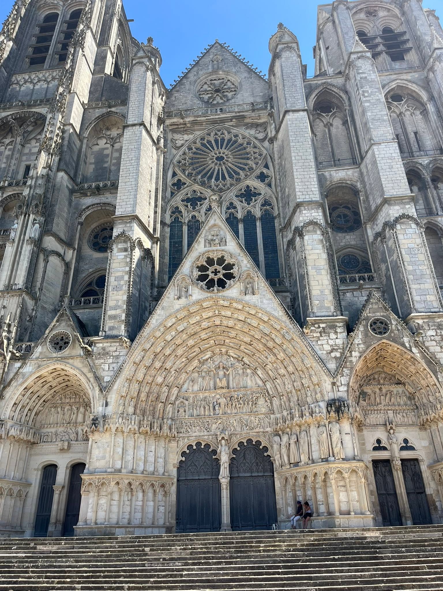 727457317_1305298405091316_1039611046943666362_n Front facade of a Gothic cathedral with a large rose window and ornate stone carvings above the entrance steps